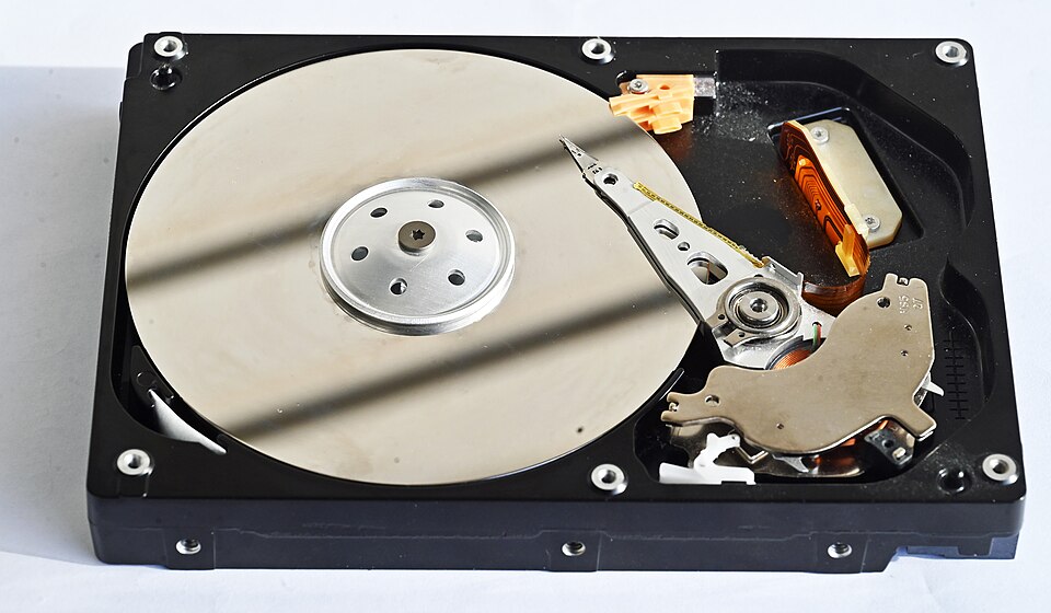 Inside an opened hard disk drive: the stacked platters and the read/write head on its actuator arm